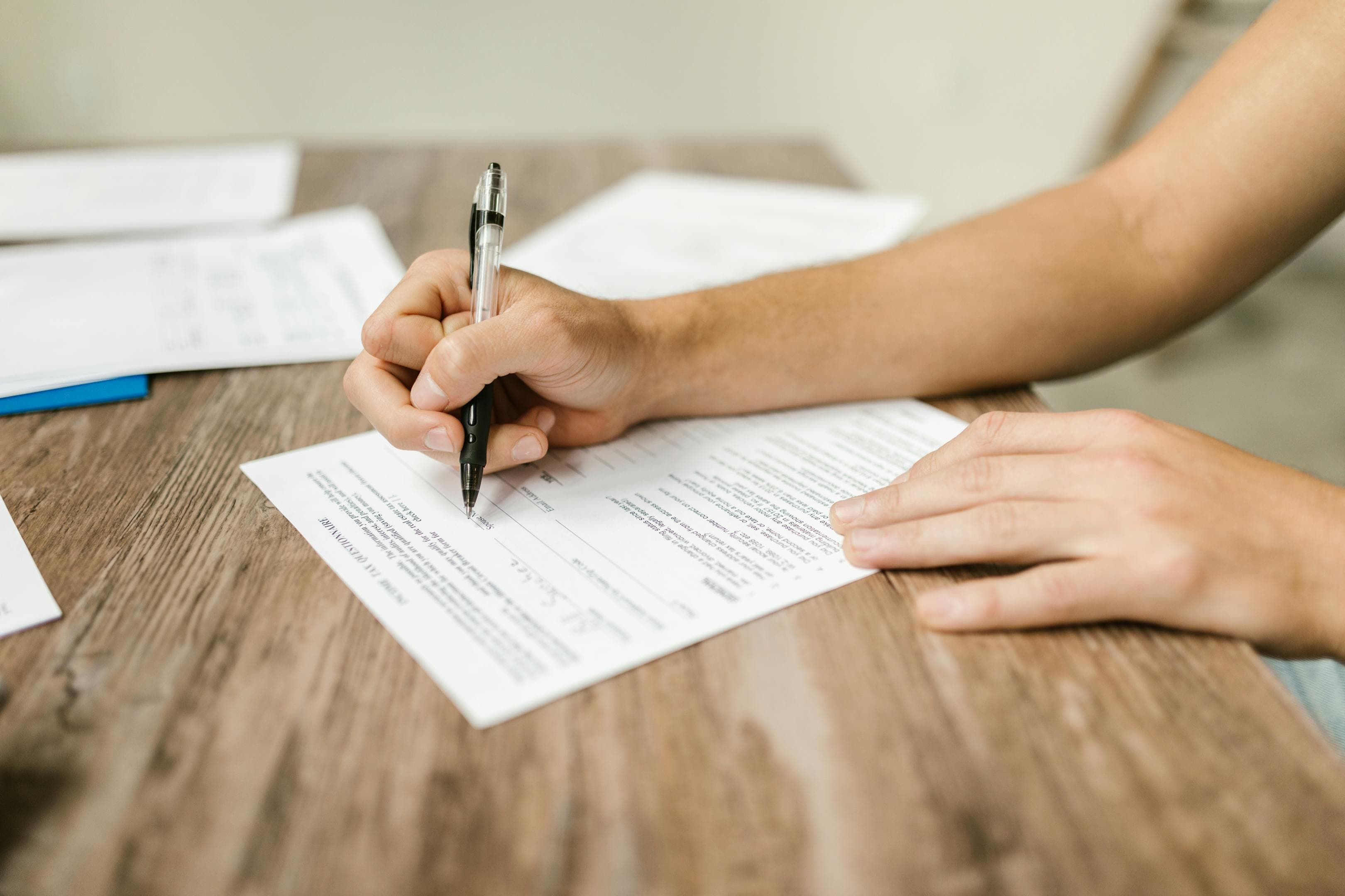 Nahaufnahme einer Hand beim Ausfüllen eines Förderantrags-Formulars mit Stift