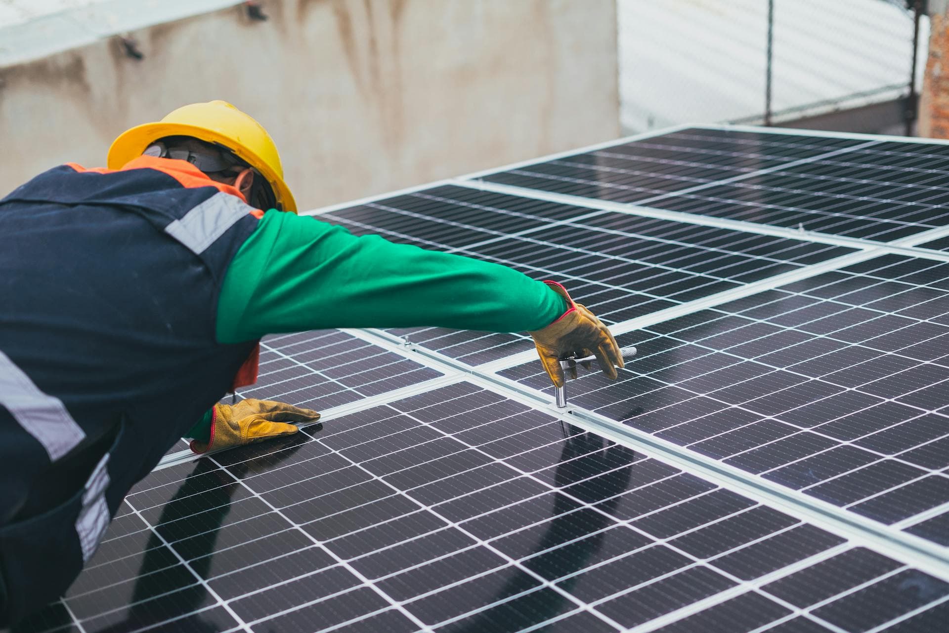 Solartechniker in Schutzausrüstung wartet eine Photovoltaikanlage auf dem Dach