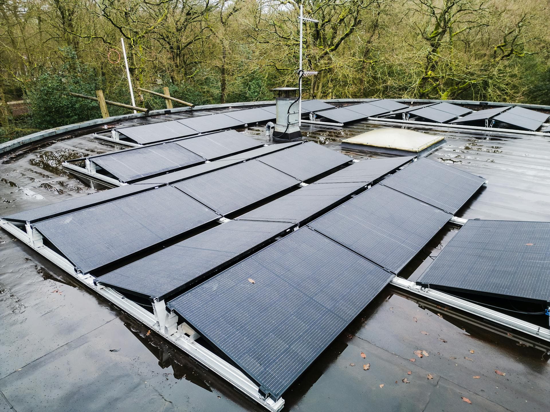 Einfamilienhaus mit Solaranlage auf dem Dach und Wärmepumpe-Außeneinheit im Garten