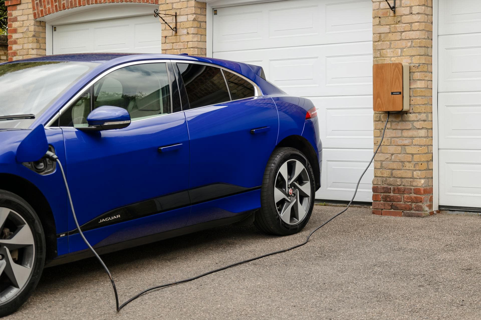 Einfamilienhaus mit wandmontierter Wallbox und ladendem Elektroauto